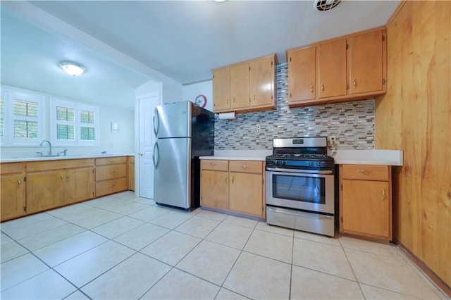 kitchen with backsplash, sink, light tile patterned floors, and stainless steel appliances