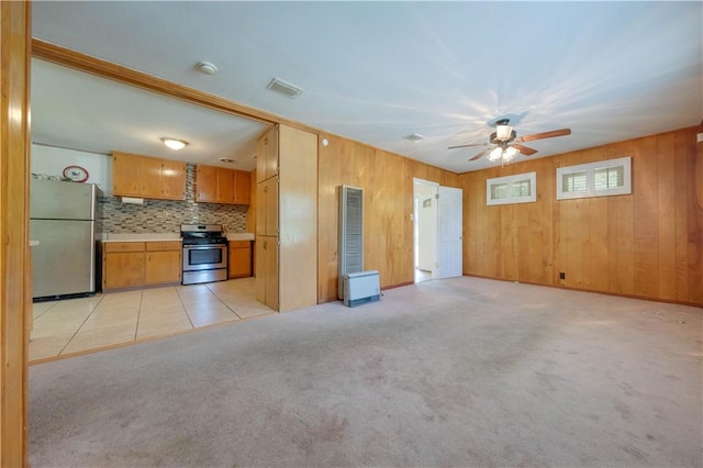 kitchen with appliances with stainless steel finishes, tasteful backsplash, ceiling fan, wooden walls, and light carpet