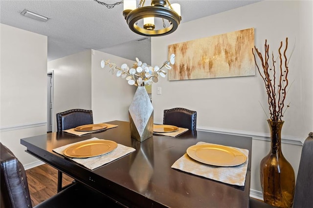 dining room featuring hardwood / wood-style flooring, a textured ceiling, and an inviting chandelier