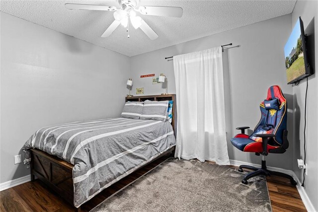 bedroom featuring dark wood-type flooring, a textured ceiling, and ceiling fan