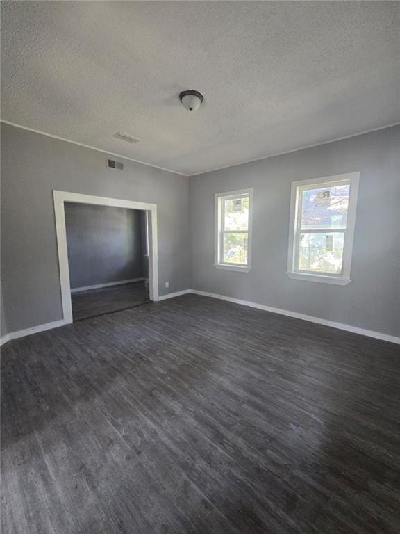 spare room with dark hardwood / wood-style flooring and a textured ceiling