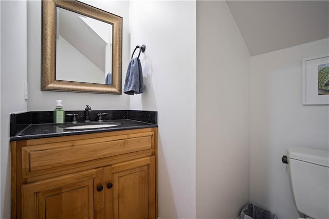 bathroom featuring vaulted ceiling, toilet, and vanity