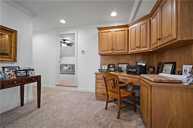 carpeted home office featuring built in desk, ceiling fan, and ornamental molding