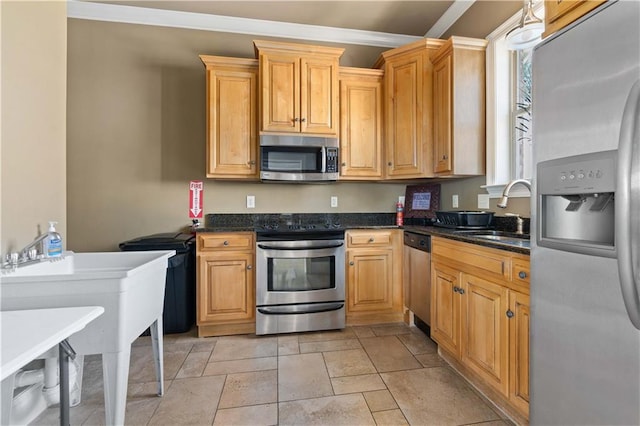 kitchen featuring crown molding, stainless steel appliances, sink, and dark stone countertops