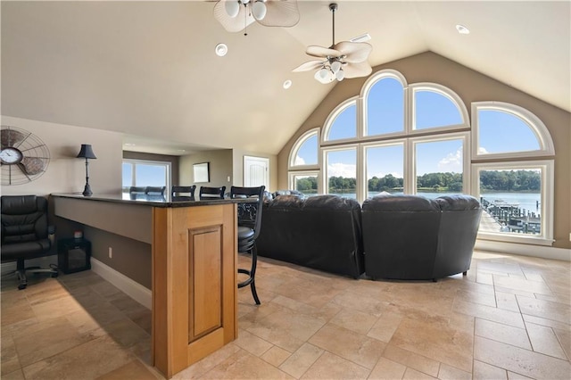 interior space with ceiling fan, high vaulted ceiling, and a water view