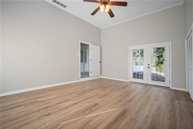 spare room with ceiling fan, french doors, a high ceiling, crown molding, and light hardwood / wood-style flooring