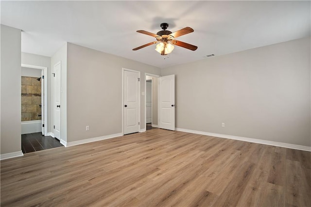 unfurnished bedroom with ensuite bathroom, ceiling fan, and wood-type flooring