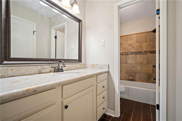 full bathroom featuring tiled shower / bath, vanity, and toilet