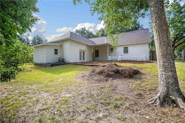 back of house with central AC unit and a lawn