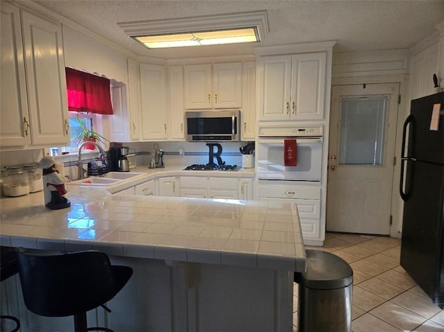1832 Aden Rd, Mobile, AL 36695 - kitchen with appliances with stainless steel finishes, a sink, tile countertops, a peninsula, and a textured ceiling