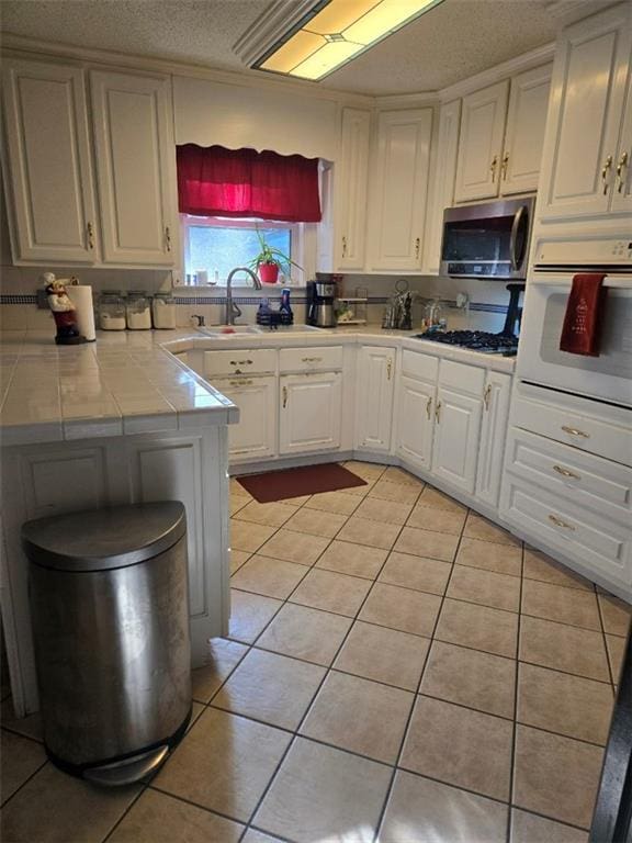 1832 Aden Rd, Mobile, AL 36695 - kitchen with oven, stainless steel microwave, a sink, light tile patterned flooring, and a textured ceiling