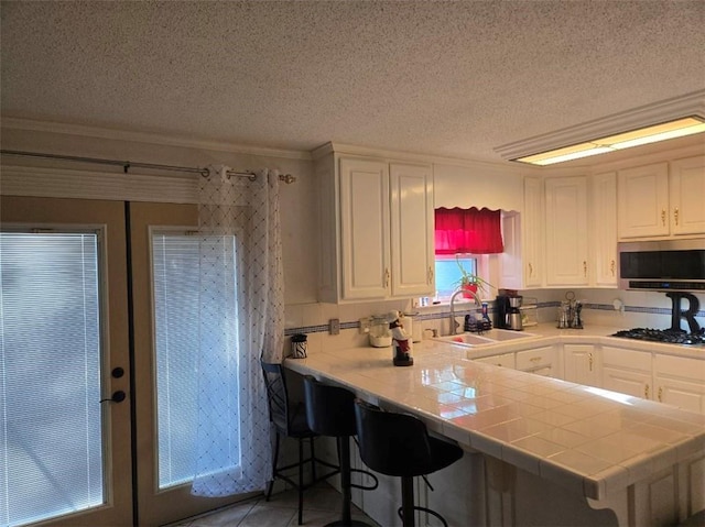 1832 Aden Rd, Mobile, AL 36695 - kitchen with stainless steel microwave, a sink, white cabinetry, a textured ceiling, and ornamental molding