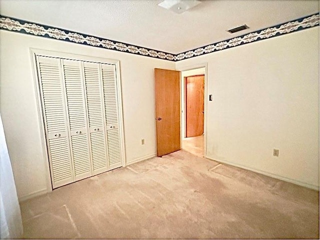 unfurnished bedroom featuring a textured ceiling, light carpet, and a closet