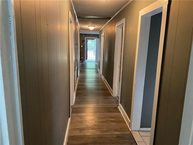 hall with hardwood / wood-style flooring, a textured ceiling, and ornamental molding