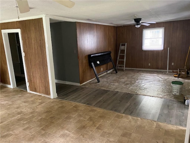 unfurnished room with wood walls, ceiling fan, wood-type flooring, and ornamental molding