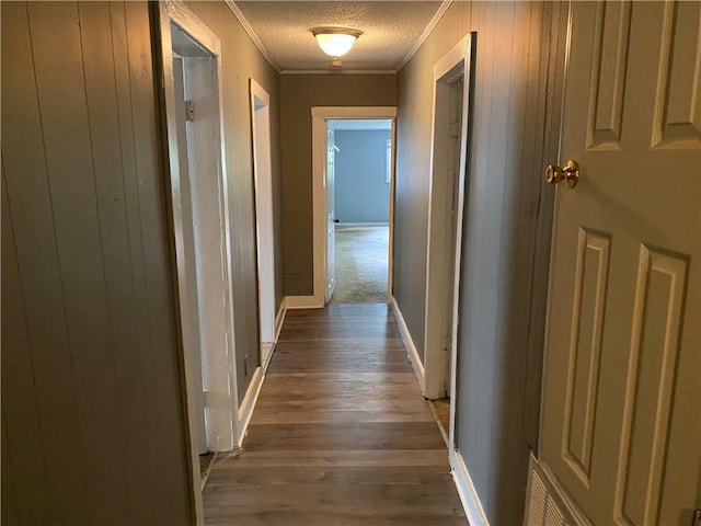 corridor featuring dark hardwood / wood-style floors, ornamental molding, and a textured ceiling