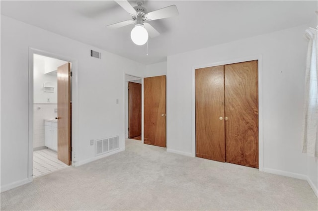 unfurnished bedroom with light carpet, ensuite bathroom, a closet, and ceiling fan