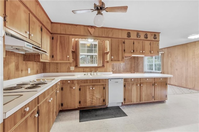 kitchen with white appliances, ceiling fan, wooden walls, and sink