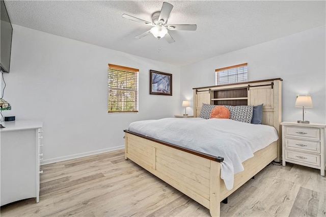 bedroom featuring ceiling fan, a textured ceiling, and light hardwood / wood-style flooring