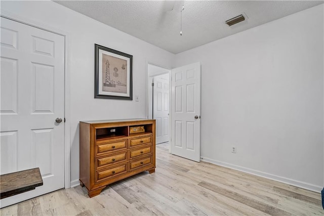 bedroom with light hardwood / wood-style floors and a textured ceiling