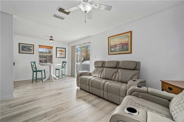 living room featuring ceiling fan, a textured ceiling, and light wood-type flooring