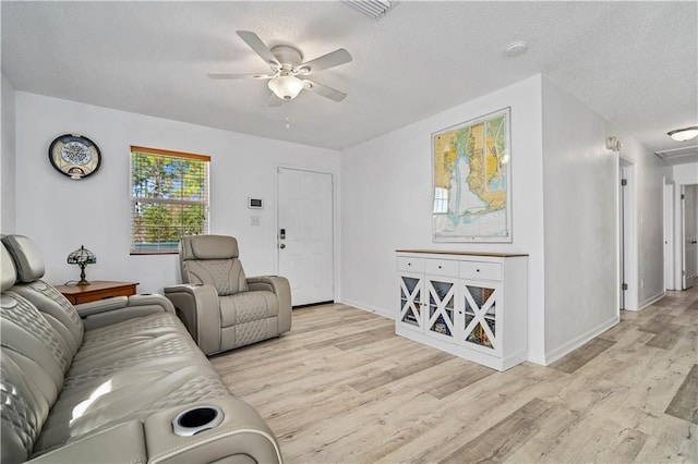 living room featuring a textured ceiling, ceiling fan, and light hardwood / wood-style flooring