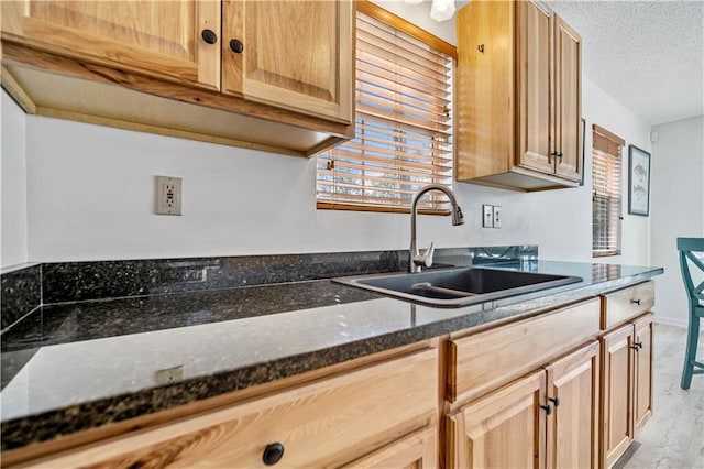 kitchen with dark stone countertops, sink, and a textured ceiling