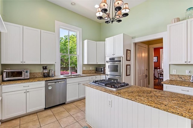 kitchen with appliances with stainless steel finishes, an inviting chandelier, a sink, and white cabinetry