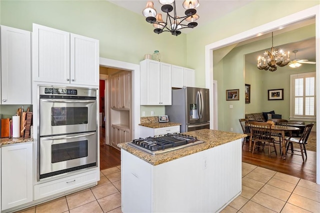 kitchen with appliances with stainless steel finishes, light tile patterned floors, a notable chandelier, and white cabinetry