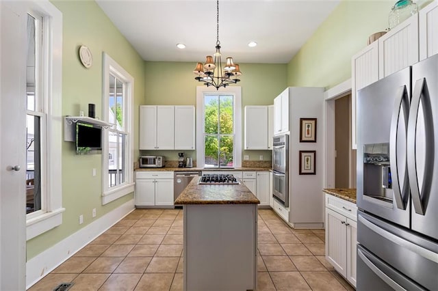 kitchen with white cabinets, a center island, an inviting chandelier, and appliances with stainless steel finishes