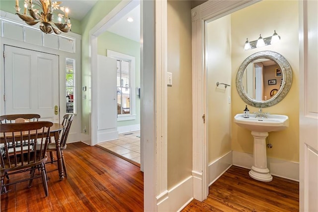 bathroom with wood finished floors, an inviting chandelier, and baseboards