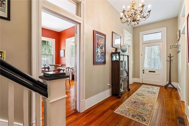 entryway with a chandelier, visible vents, hardwood / wood-style flooring, and baseboards