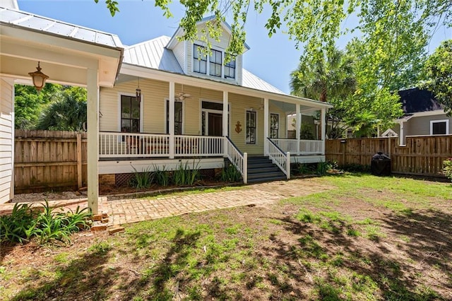 view of front of property featuring a porch, metal roof, and fence