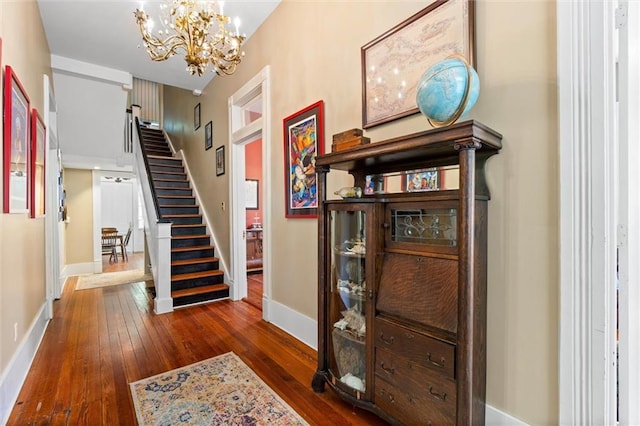 interior space with wood-type flooring, baseboards, and an inviting chandelier