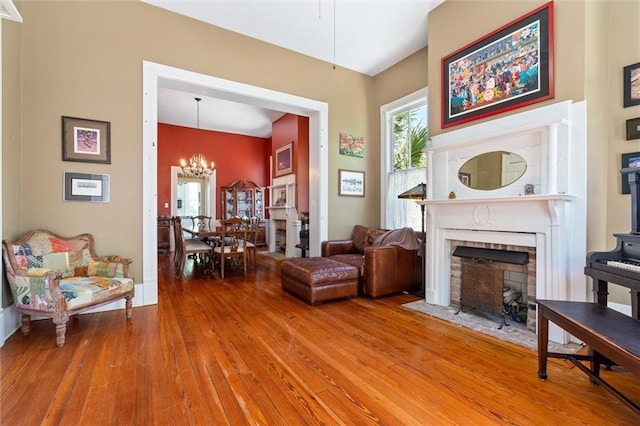 sitting room featuring a brick fireplace, a chandelier, and wood finished floors