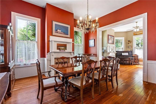 dining space with a decorative wall, an inviting chandelier, radiator heating unit, a wainscoted wall, and wood-type flooring