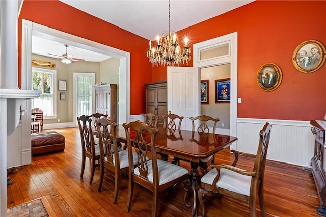 dining room featuring wainscoting, hardwood / wood-style flooring, and ceiling fan with notable chandelier