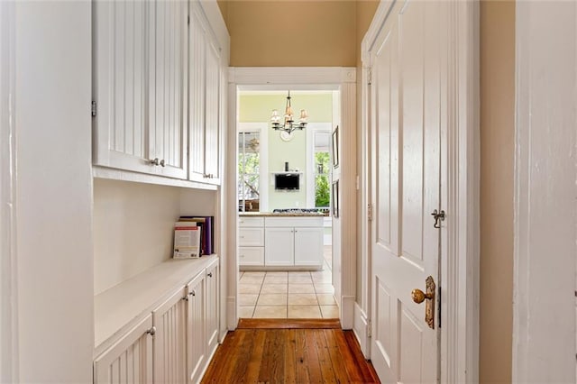 hallway with hardwood / wood-style floors and a notable chandelier