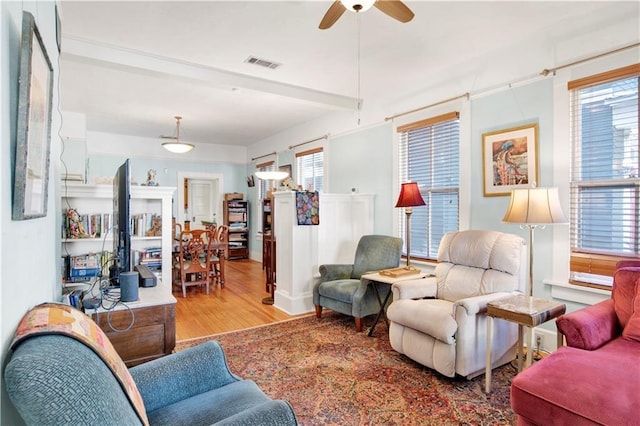 living room with ceiling fan, beamed ceiling, and light hardwood / wood-style flooring