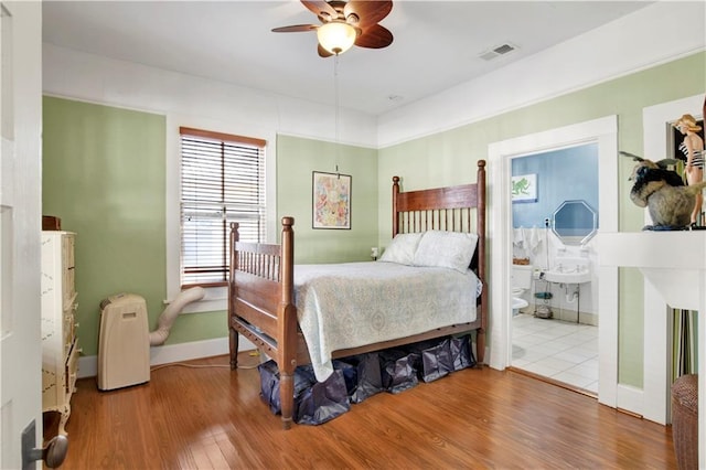 bedroom with ceiling fan, connected bathroom, and hardwood / wood-style flooring