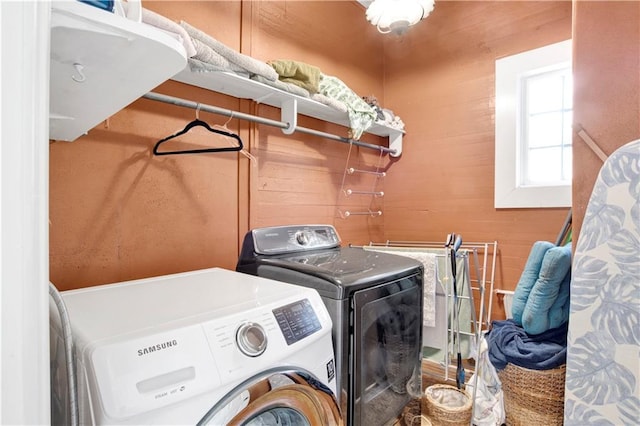 laundry room featuring wood walls and washing machine and dryer