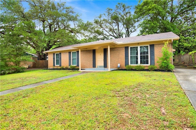 ranch-style home with brick siding, fence, and a front lawn
