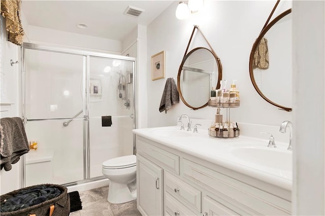 bathroom featuring a sink, double vanity, toilet, visible vents, and a stall shower