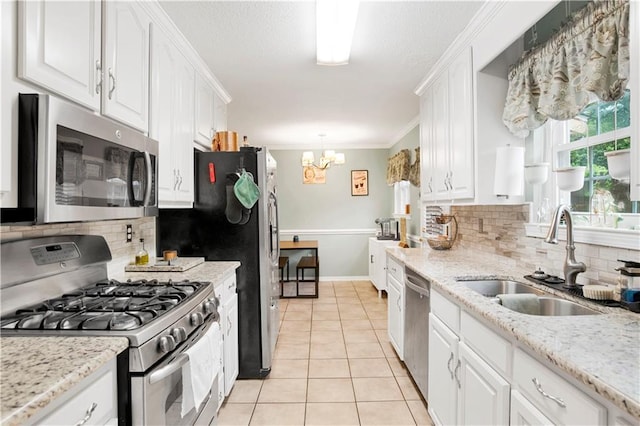 kitchen featuring white cabinets, appliances with stainless steel finishes, an inviting chandelier, a sink, and light tile patterned floors