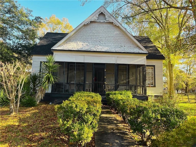 rear view of house featuring a sunroom and roof with shingles