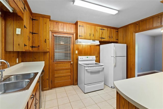 5416 Hilltop Dr N, Mobile, AL 36608 - kitchen with white appliances, under cabinet range hood, brown cabinets, wood walls, and light tile patterned flooring