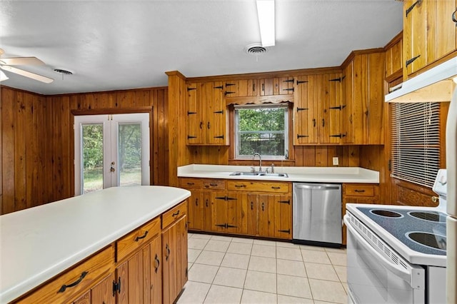5416 Hilltop Dr N, Mobile, AL 36608 - kitchen with stainless steel dishwasher, white range with electric stovetop, light countertops, brown cabinets, and wooden walls