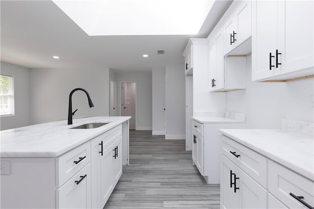 5023 Santos Dr W, Mobile, AL 36619 - kitchen featuring recessed lighting, white cabinetry, light wood finished floors, light stone counters, and a kitchen island with sink