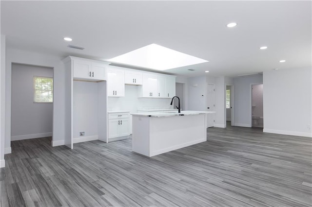 5023 Santos Dr W, Mobile, AL 36619 - kitchen featuring an island with sink, white cabinetry, recessed lighting, a skylight, and light wood-style flooring