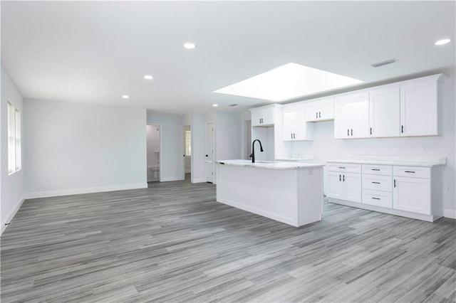 5023 Santos Dr W, Mobile, AL 36619 - kitchen with light wood-style flooring, an island with sink, white cabinets, plenty of natural light, and recessed lighting